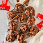 baked kit kat cookies on cooling rack on top of parchment paper with additional kit kats and kit kat wrappers scattered around.