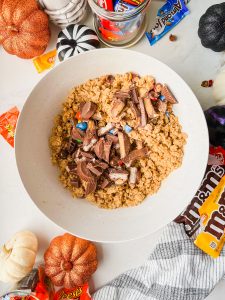 leftover halloween candy mixed into cookie dough in white mixing bowl.