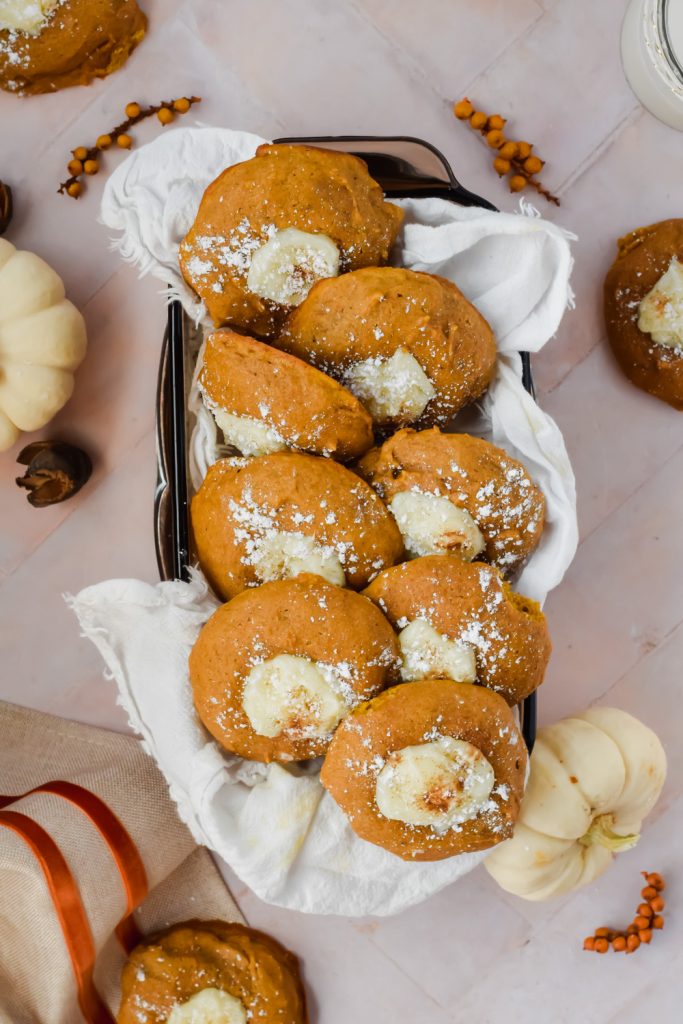 overhead shot of 8 pumpkin cheesecake cookies in rectangular dish surrounded by fall decor.