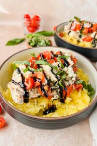 serving bowl full of spaghetti squash topped with baked feta chicken and drizzled with balsamic glaze.