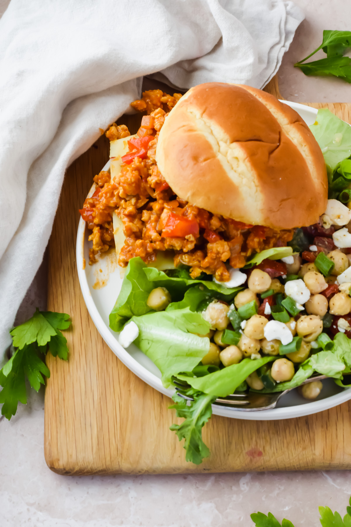 chicken sloppy joe beside mixed greens salad on white serving plate.