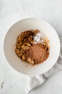 creamed butter and sugar with cocoa powder on top in white mixing bowl.