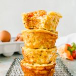 four sweet potato egg cups stacked on top of each other with a bite taken out of the top one on wire cooling rack.