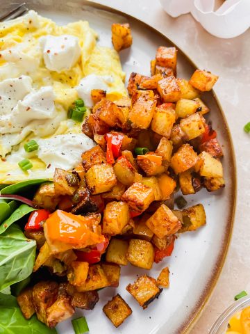 copycat ihop crispy breakfast potatoes plated beside scrambled eggs and spinach.
