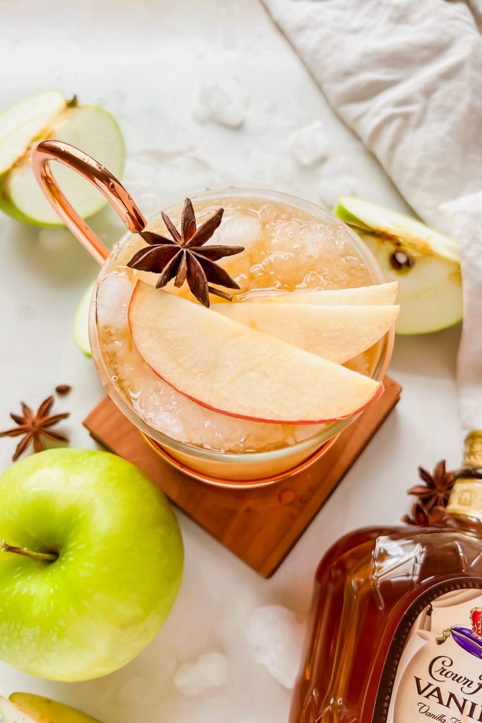 overhead shot of crown apple slush in moscow mule glass garnished with star anise and apple slices.