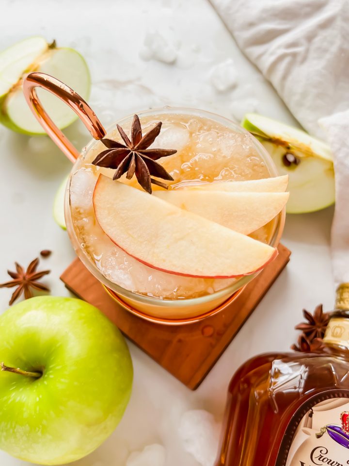 overhead shot of crown apple slush in moscow mule glass garnished with star anise and apple slices.