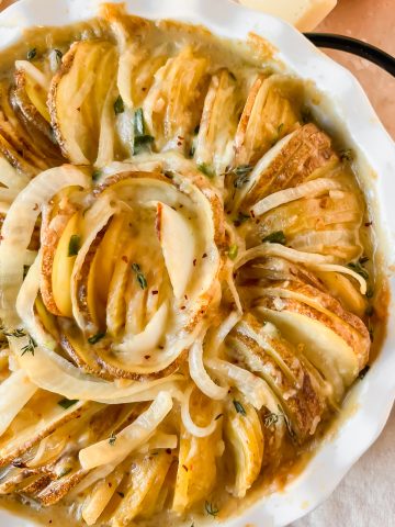 baked french onion potatoes in white pie dish.