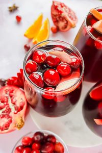glass full of thanksgiving sangria garnished with cranberries and apple slices.
