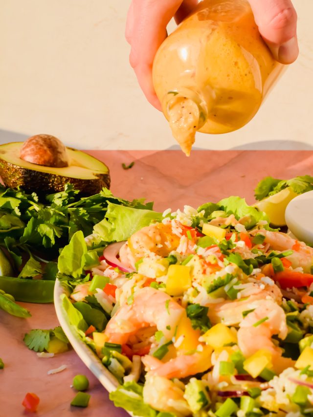 shrimp and mango salad being dressed with sweet onion and citrus dressing.