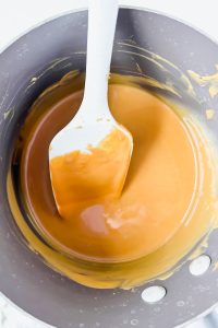melted peanut butter in sauce pot with white spatula in pot.
