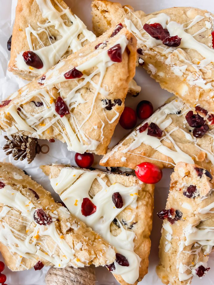cranberry white chocolate bars drizzled with white chocolate cut into triangles and stacked on top of each other.