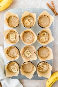 muffin tin lined with parchment cupcake liners filled with greek yogurt banana muffin batter.