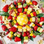 holiday charcuterie wreath featuring fresh fruit, cheese, and meats arranged on skewers.