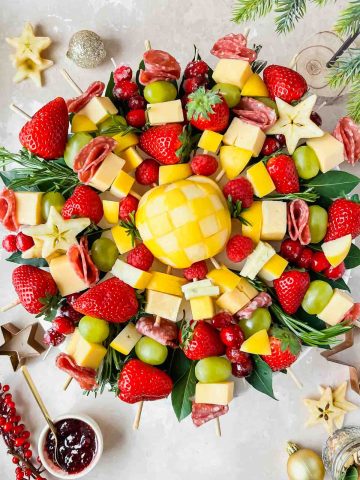 holiday charcuterie wreath featuring fresh fruit, cheese, and meats arranged on skewers.