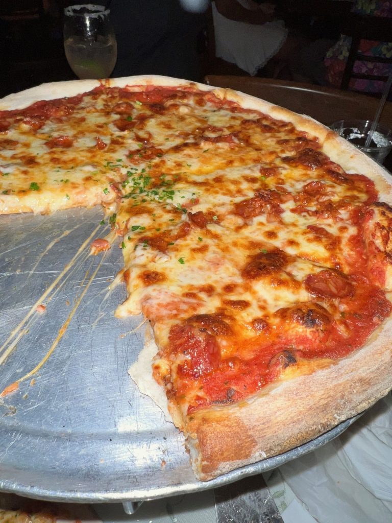 three-quarters of a large cheese pizza on silver serving tray. 