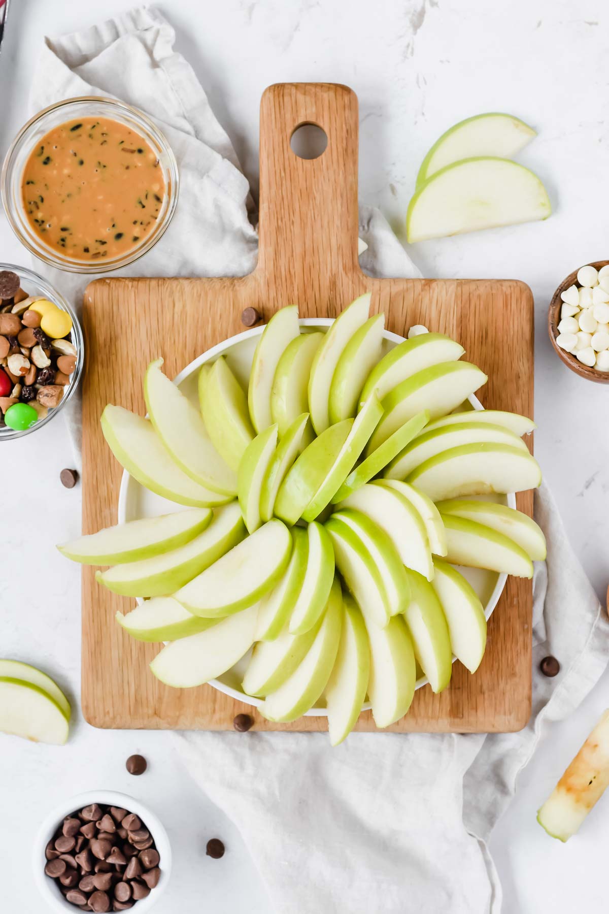 green apple sliced finely and layered in a spiral on wooden cutting board.