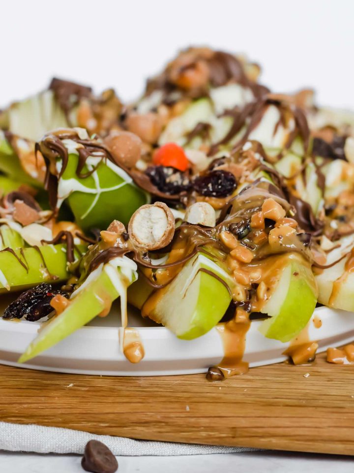 close up view of apple nachos toppings on a wooden cutting board.