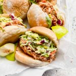 six pulled bbq chicken sliders on their side with chicken and fresh slaw pouring out.