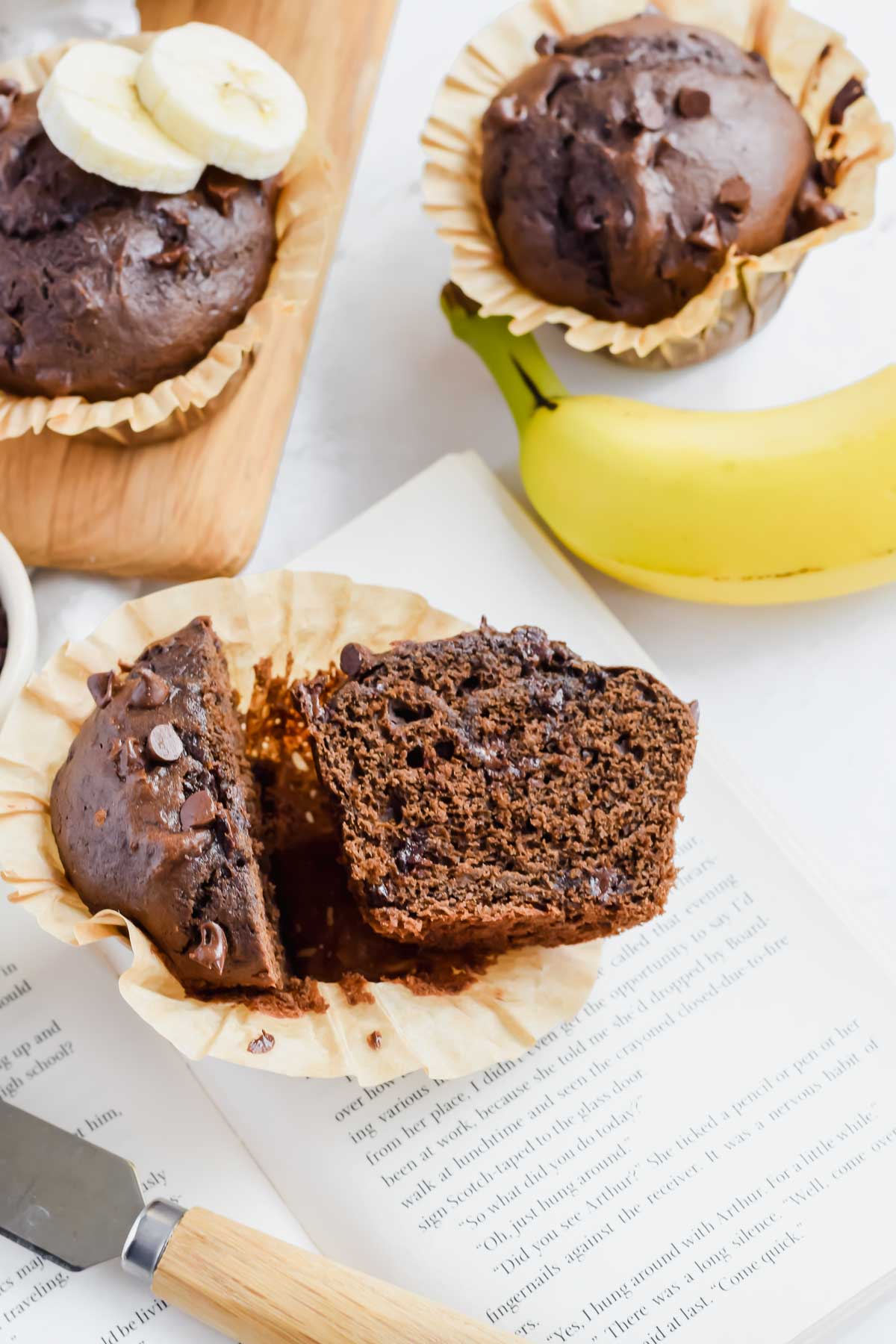 One Bowl Double Chocolate Banana Muffin cut in half in a paper muffin liner.