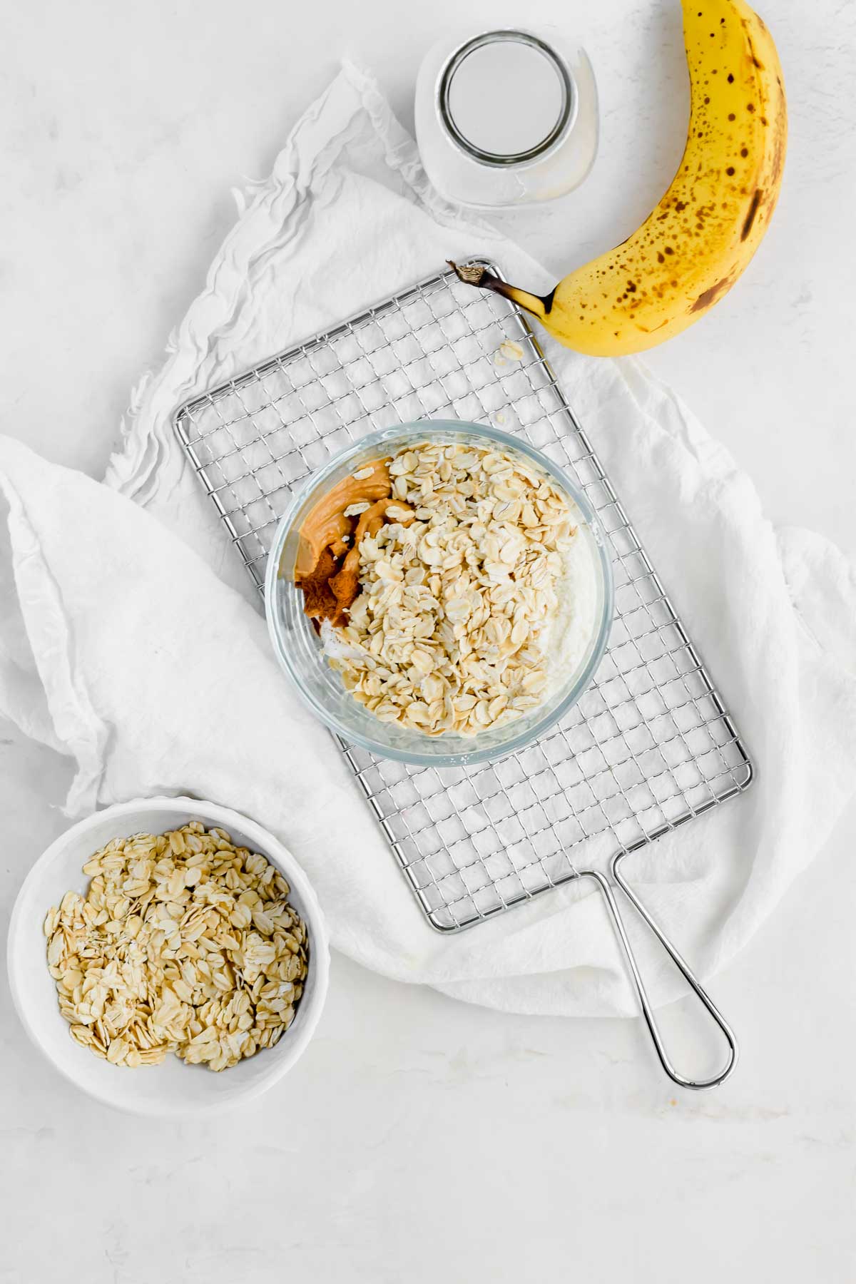 Banana Peanut Butter Overnight Oats in a small glass bowl next to a banana.