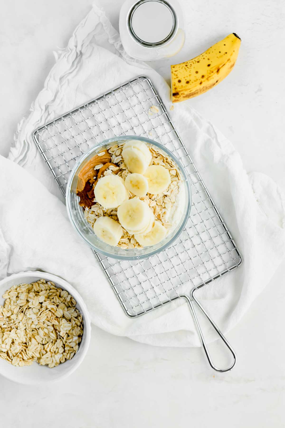 Banana Peanut Butter Overnight Oats in a small glass bowl next to half a banana and a tall glass of milk.