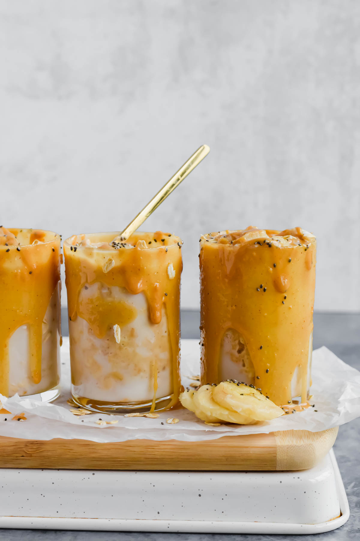 three glasses doused in peanut butter on the rim and filled with overnight oats.