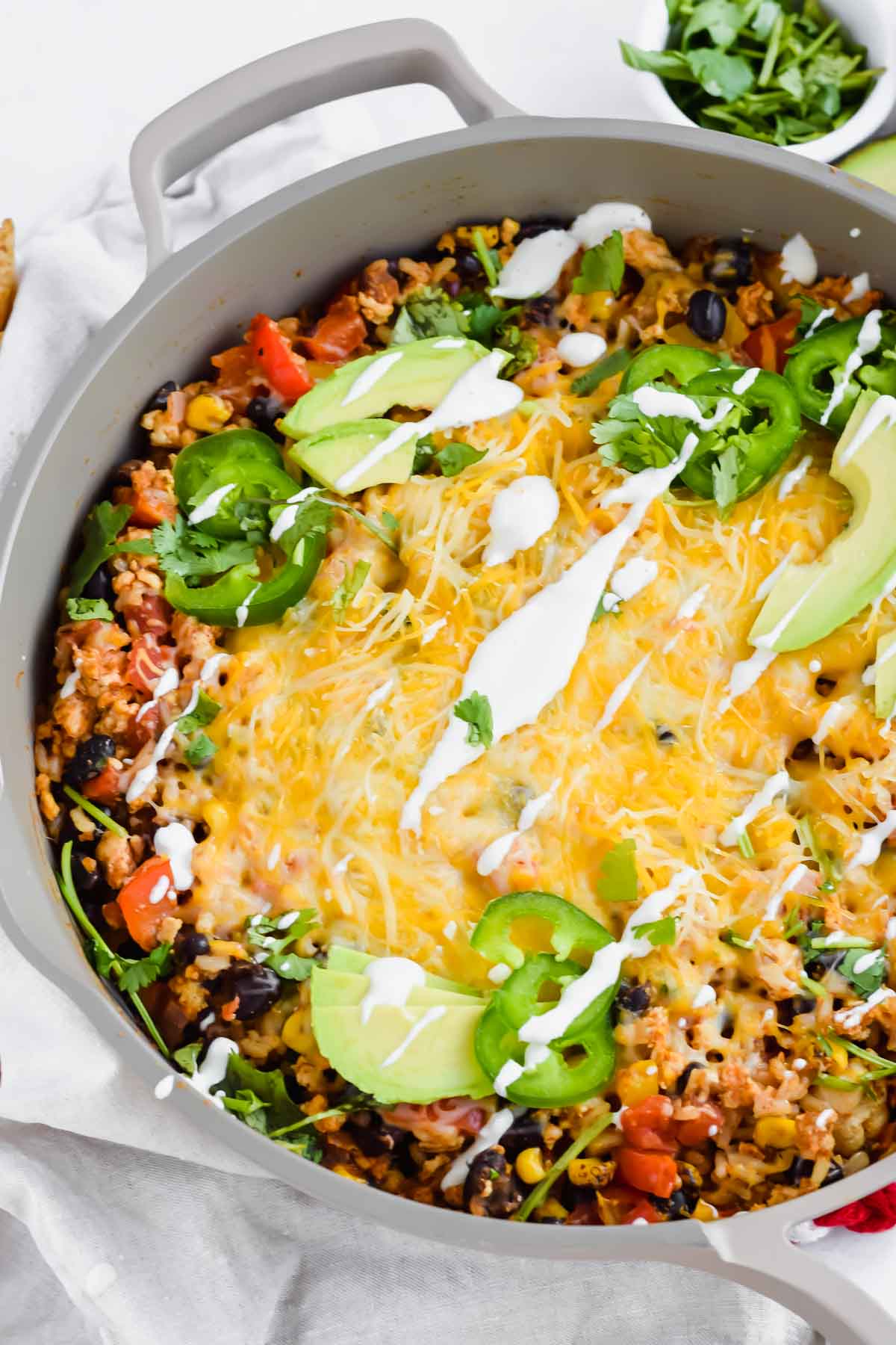 Close up of Cheesy Mexican Chicken Skillet topped with avocado and sour cream in a grey pan.