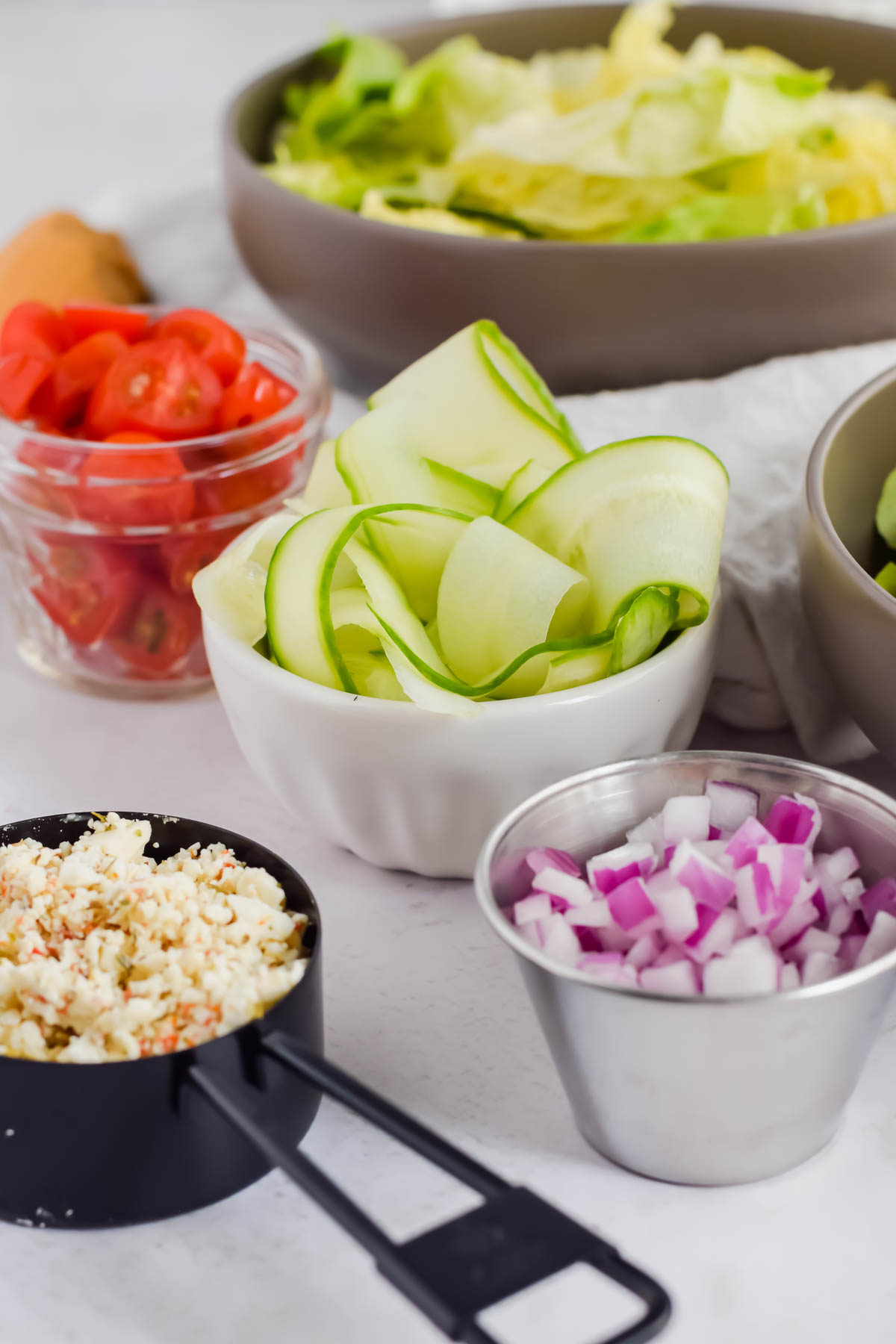 cucumber ribbons, diced red onion and crumbled feta cheese in individual bowls.