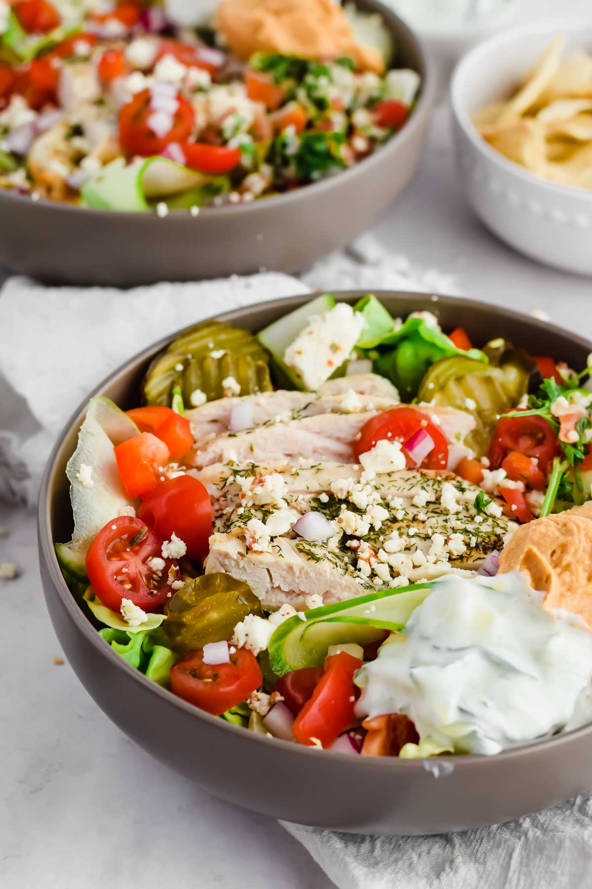loaded Mediterranean salad with chicken, pita, tomatoes, red onions, pickles, hummus, tabbouleh, and tzatziki.