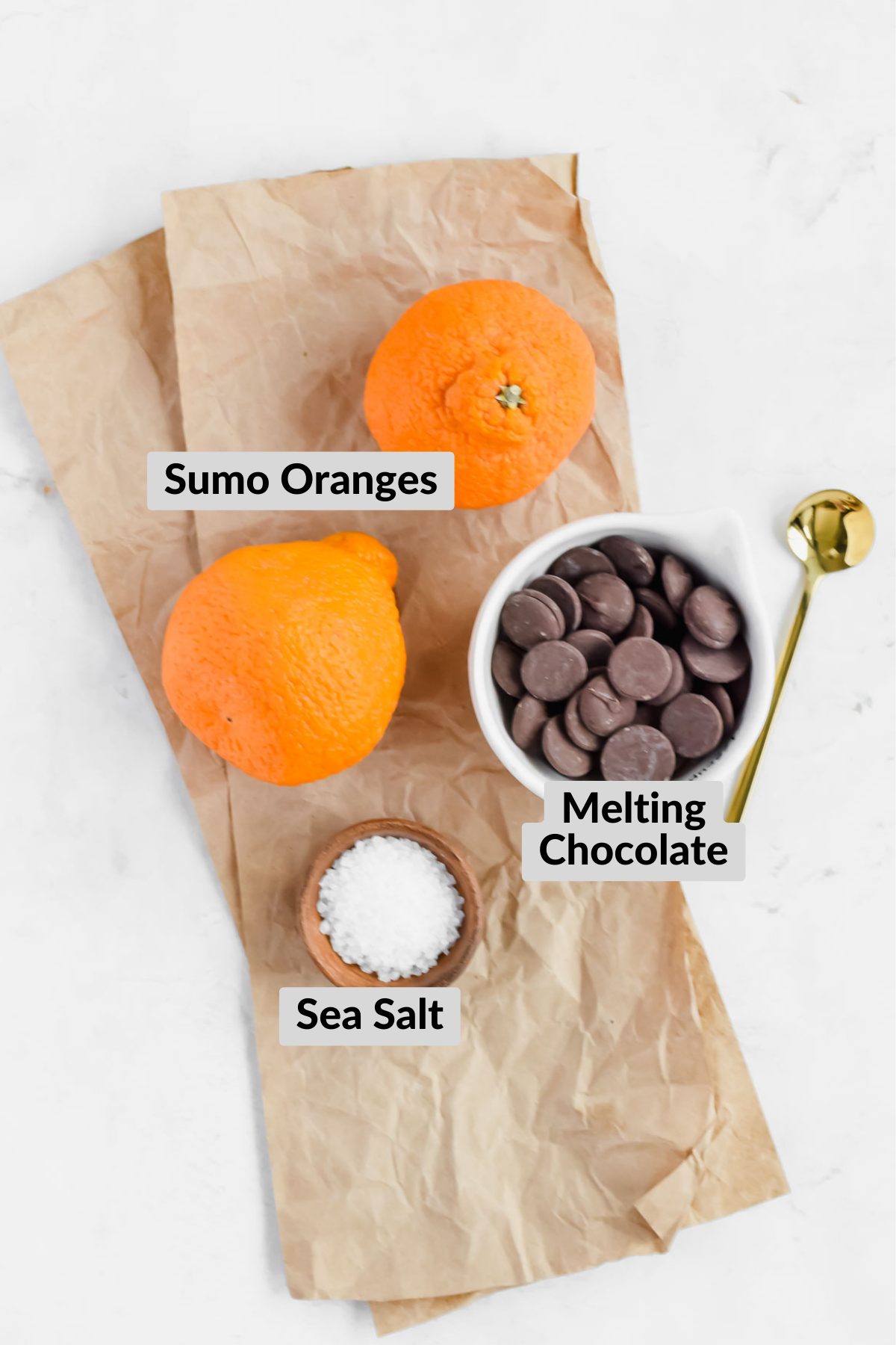 ingredients for chocolate covered oranges on parchment papper on white background.
