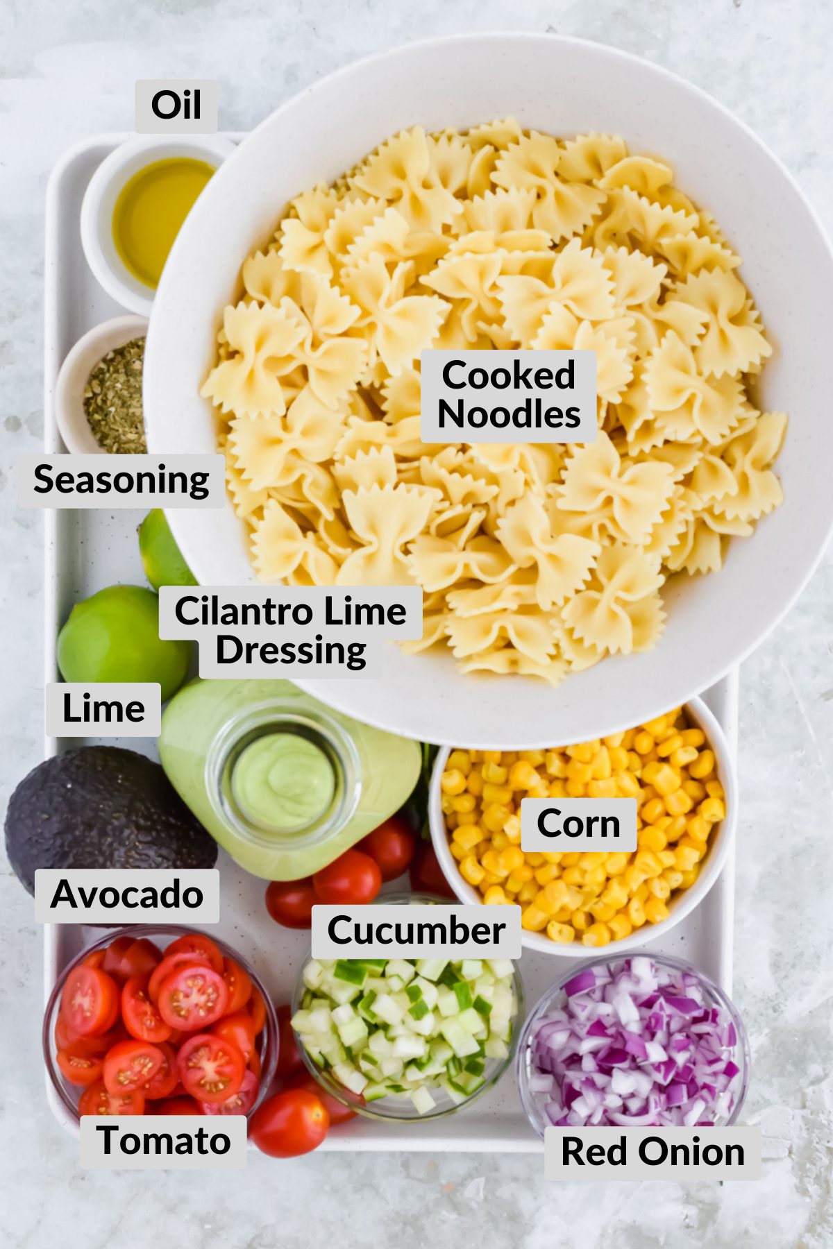 ingredients for cilantro lime pasta salad in individual bowls on white baking tray.