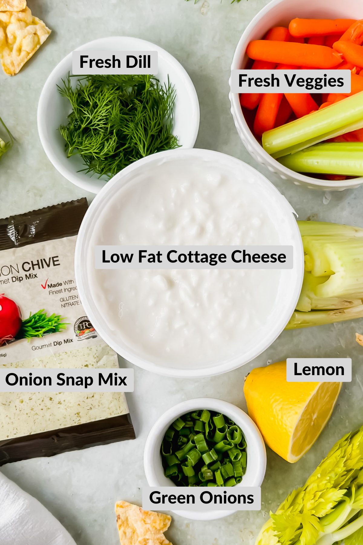 ingredients for cottage cheese chip dip in individual white bowls spread on gray background.