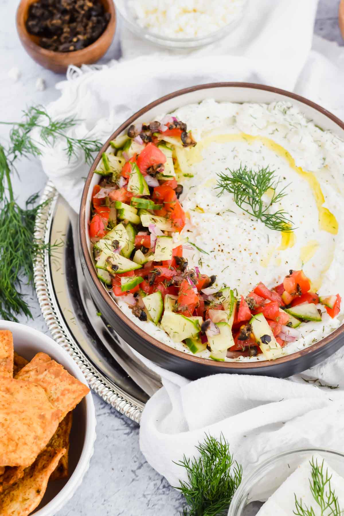 dill feta dip garnished with dill, cucumbers, tomatoes, and olives.