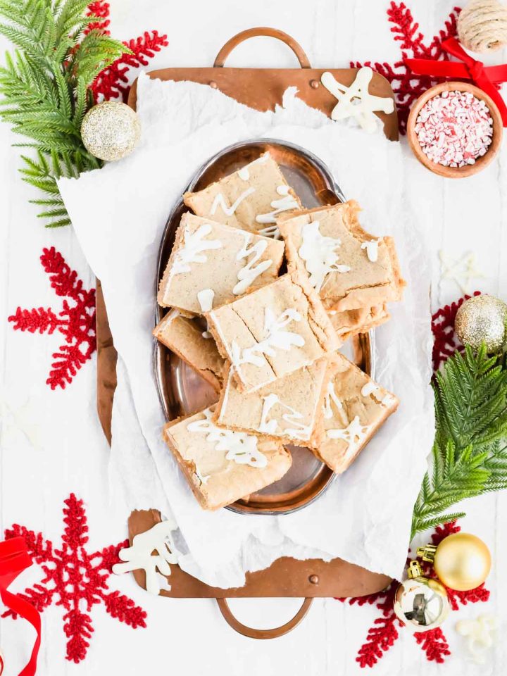Overhead shot of Gingerbread Blondies with white chocolate on a silver serving platter with a bite taken out of one.