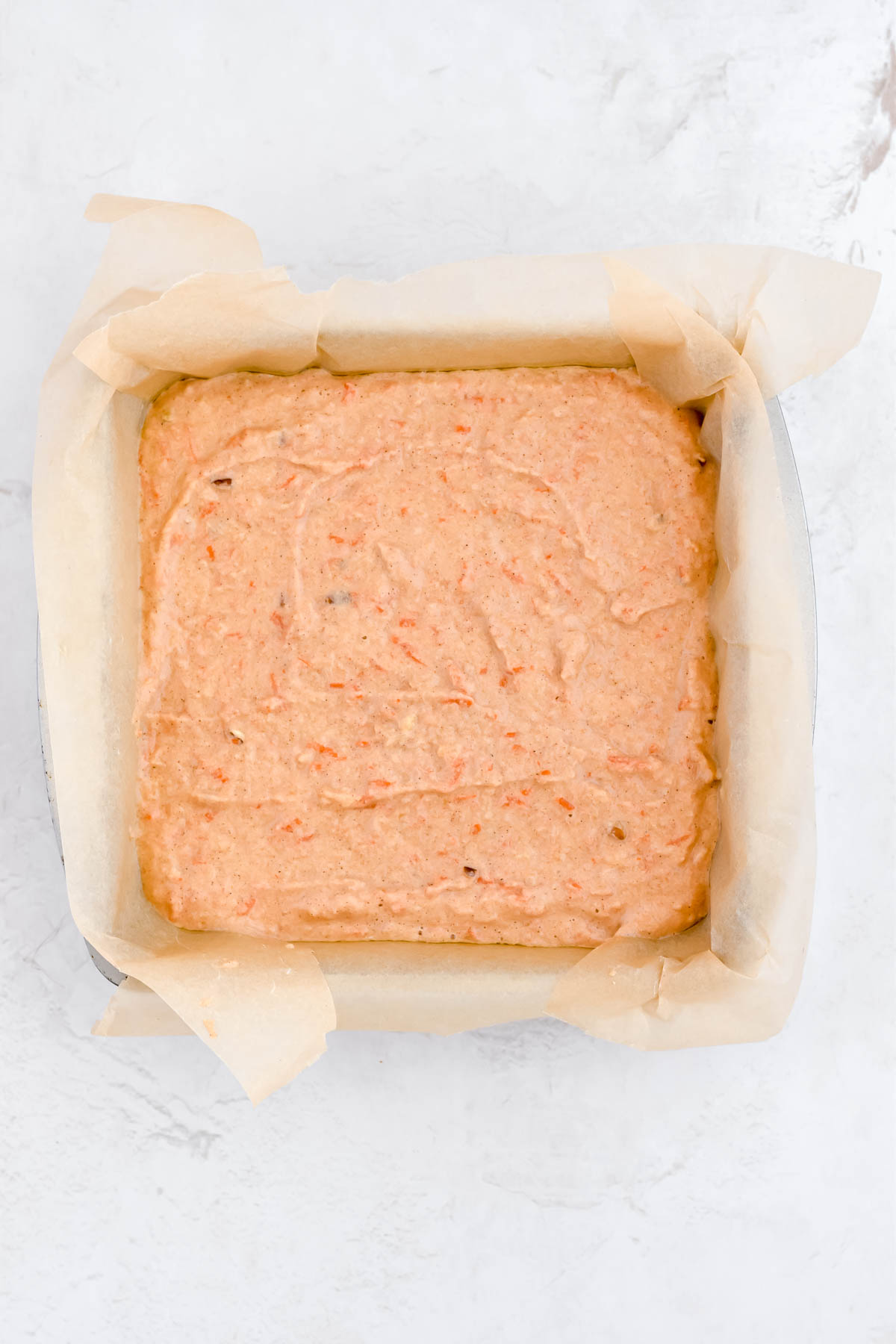 healthier carrot cake bars batter in a 9x9 pan before baking.