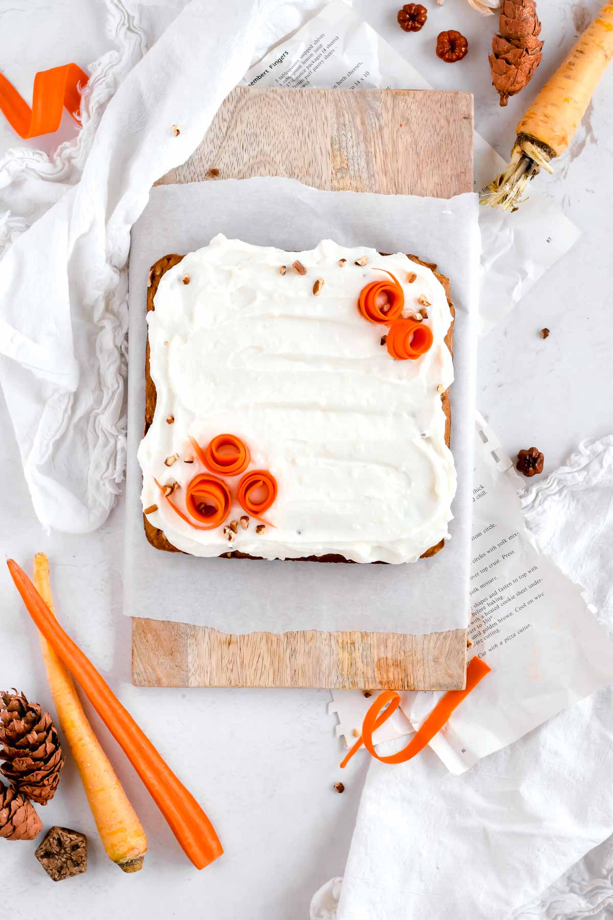 carrot cake bars with cream cheese icing topped with shredded carrots.