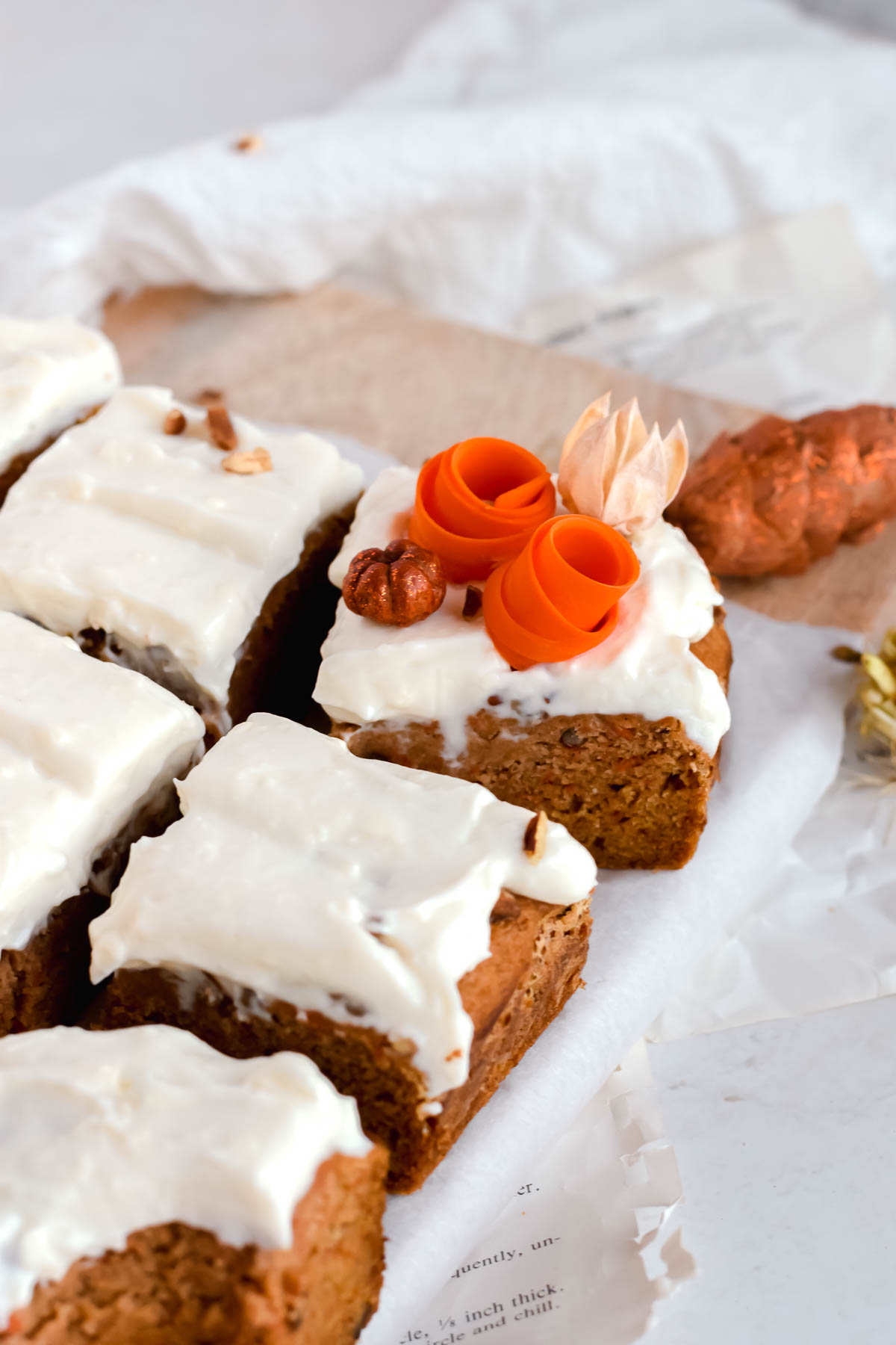 Square slices of carrot cake bars topped with cream cheese icing.
