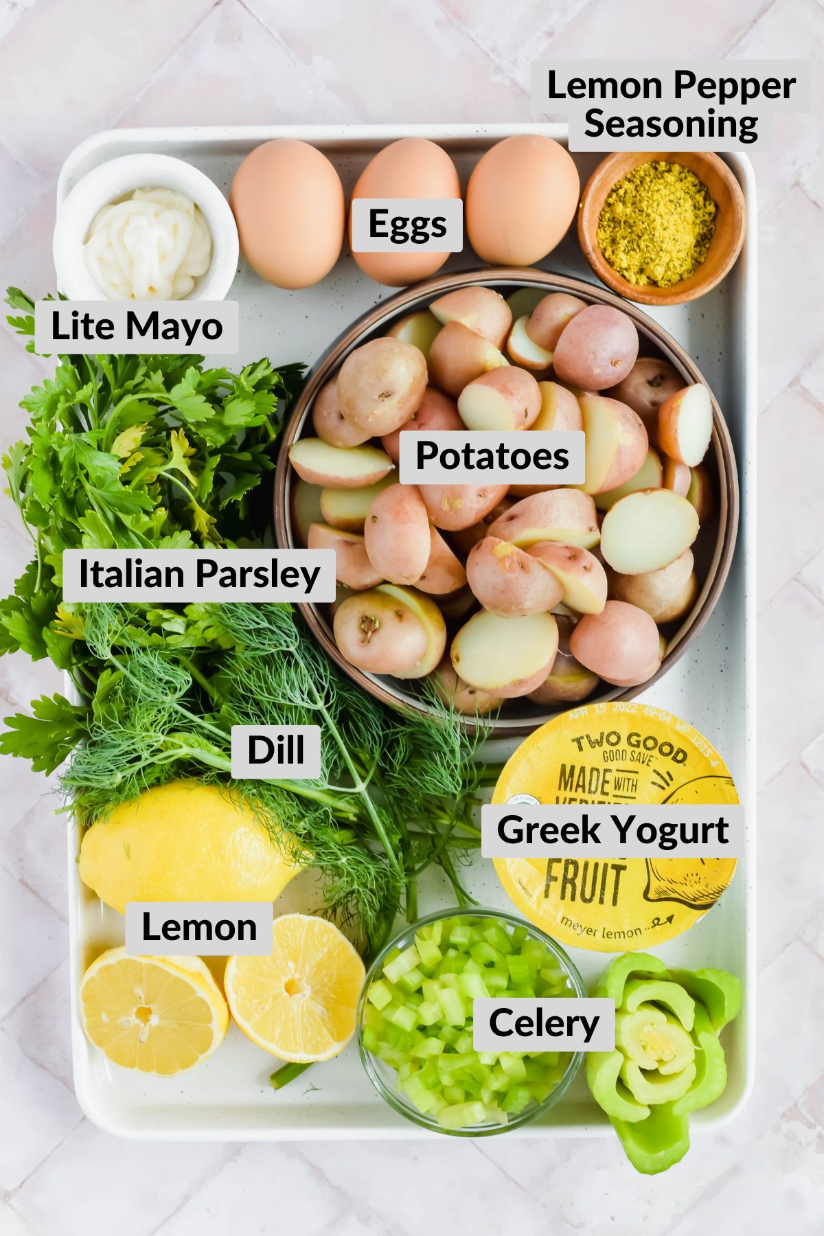 ingredients for healthy lemon dill potato salad on white baking sheet on white background.