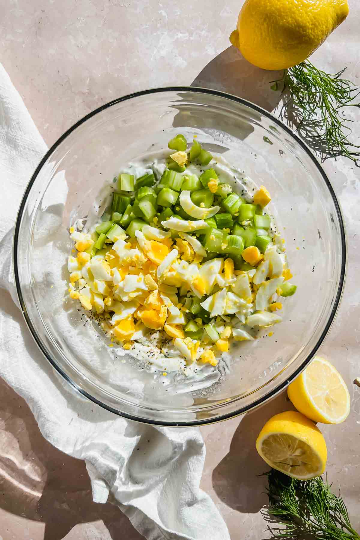 celery and diced hard boiled eggs in glass mixing bowl.