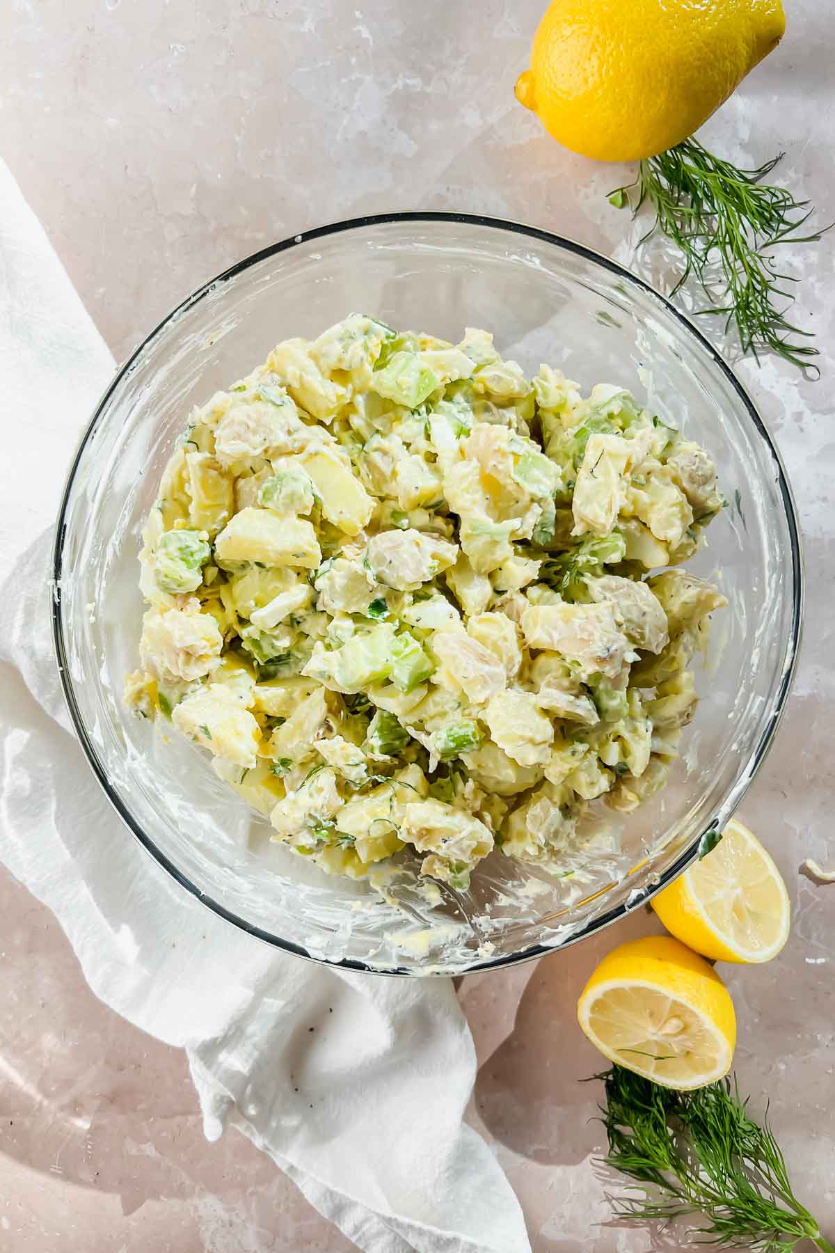 potatoes and dressing mixture mixed together in clear glass bowl.
