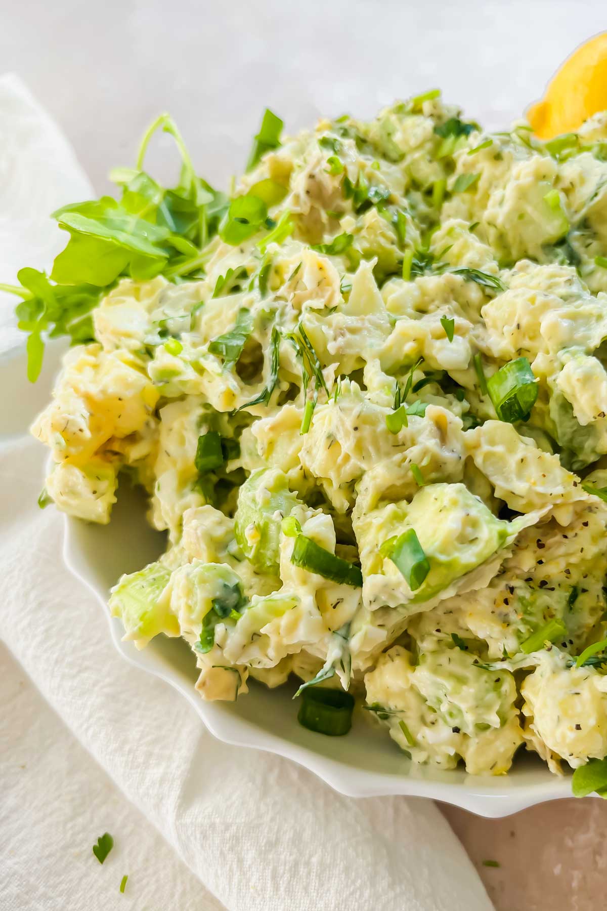 creamy healthy lemon dill potato salad mixed together garnished with lime wedges and fresh herbs.