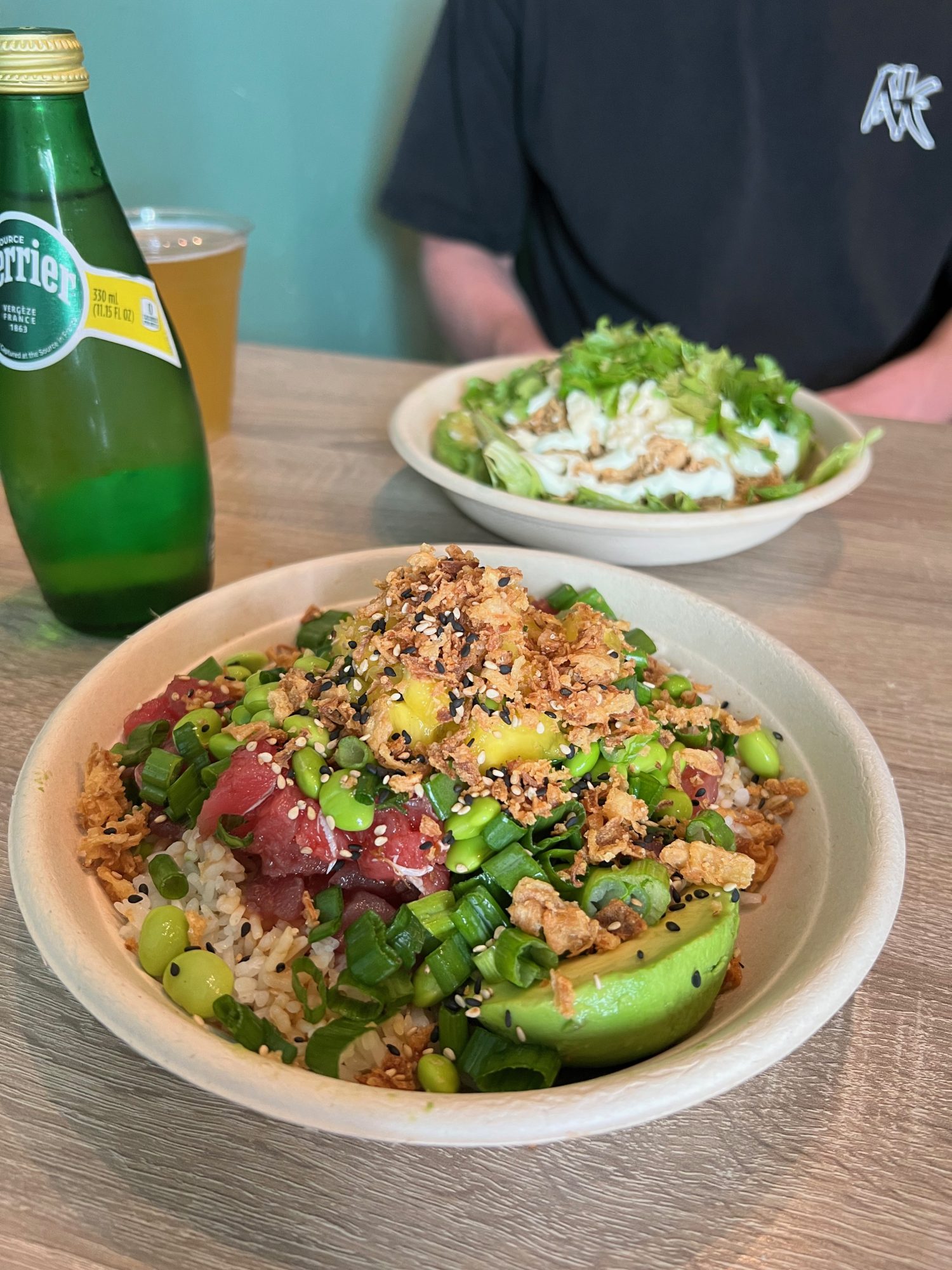 compostable poke bowl filled with rice, tuna, edamame, and topped with crispy rice and mangoes.