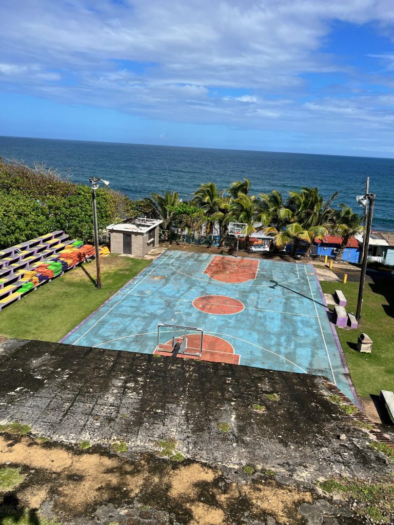 dated blue and orange basketball court overlooking on the Caribbean sea. 