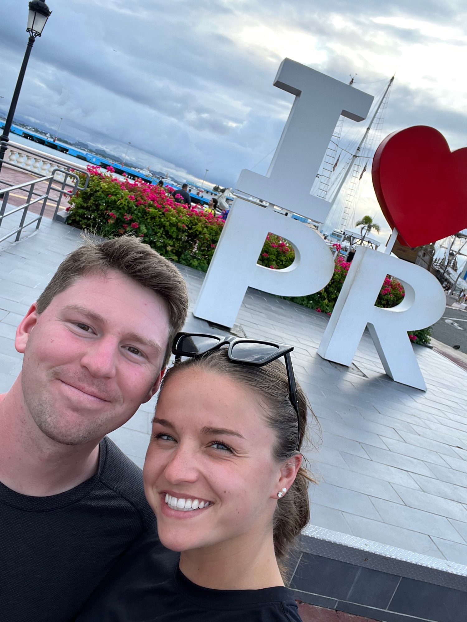 man and woman taking a selfie in front of the 'I heart PR' sign.