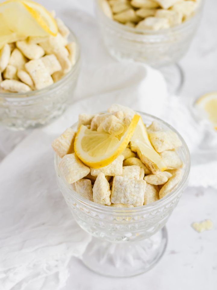 three glasses of lemon puppy chow topped with slices of lemon.