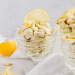 close up image of lemon puppy chow in glass container topped with slice of lemon.