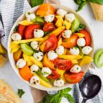 Mango tomato Salad in a large round bowl with additional ingredients surrounding.