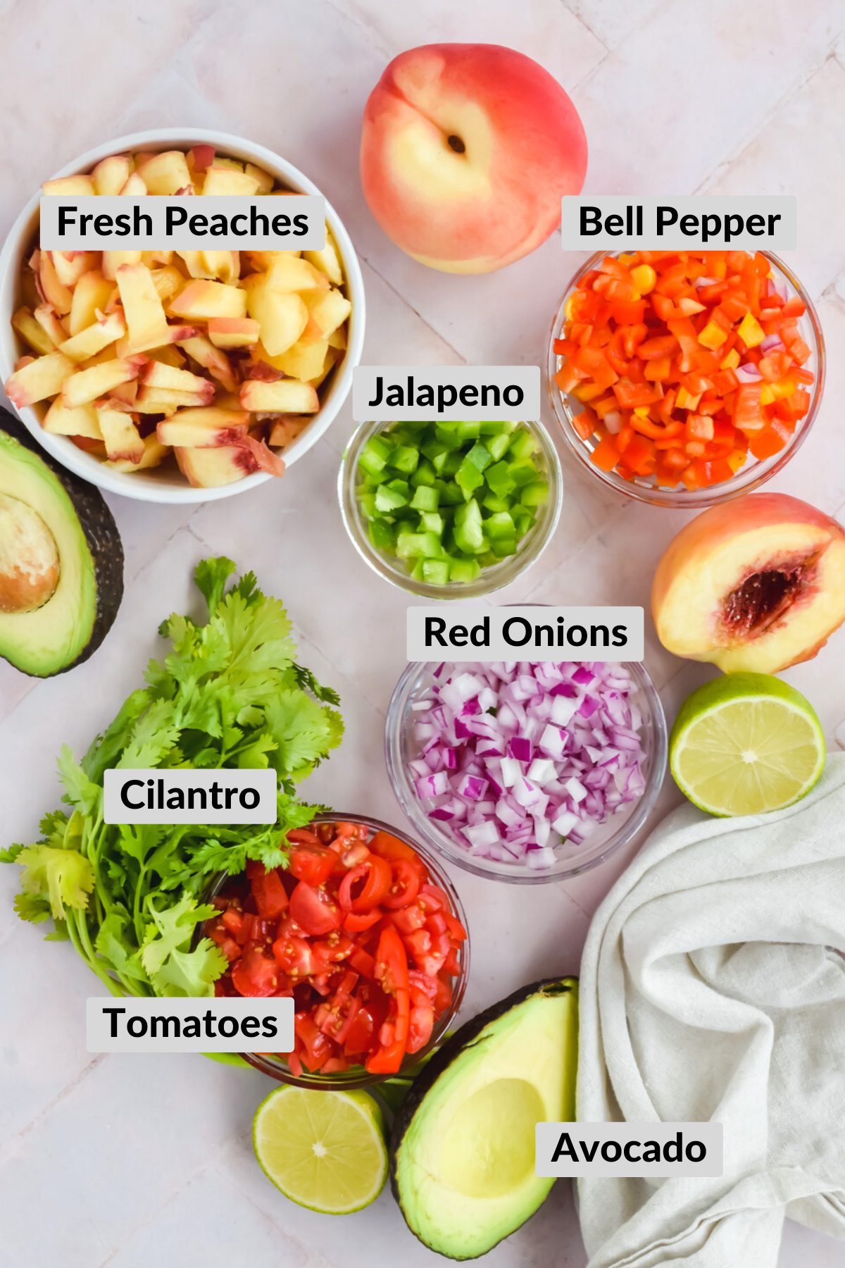 Ingredients for jalapeno peach salsa chopped in individual bowls including peaches, peppers, onions, cilantro, avocado, and lime on stone white background.