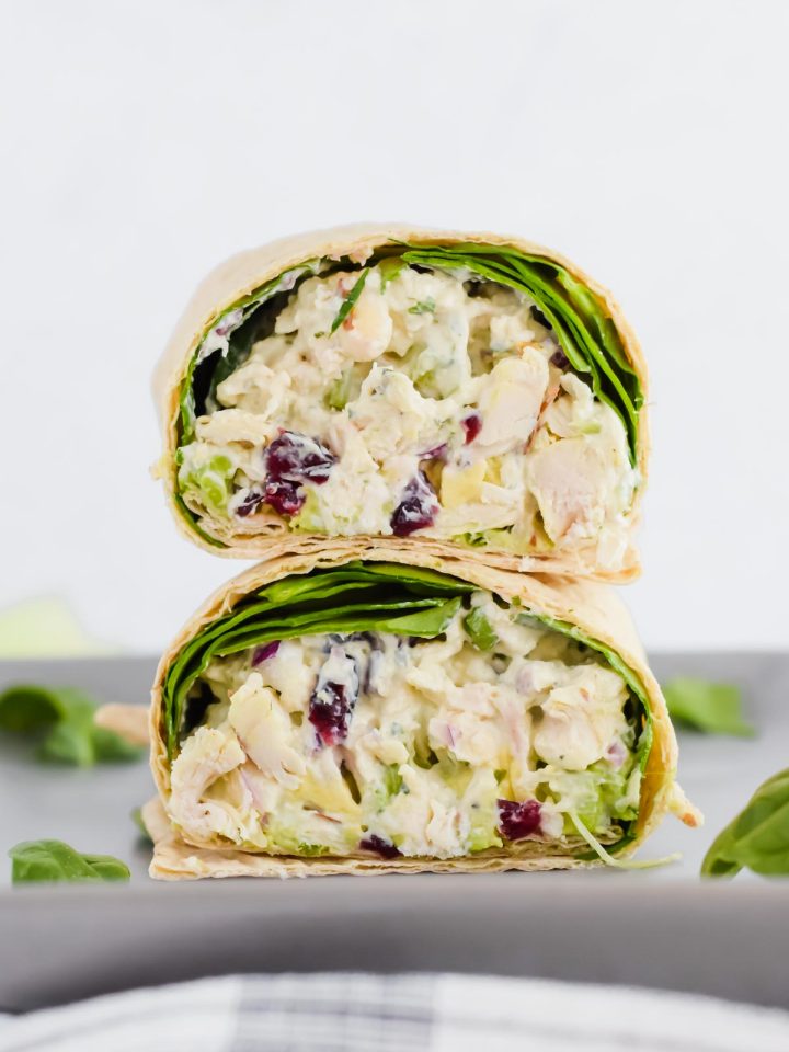 healthy pesto chicken salad in a wheat wrap on a grey plate with concrete background.