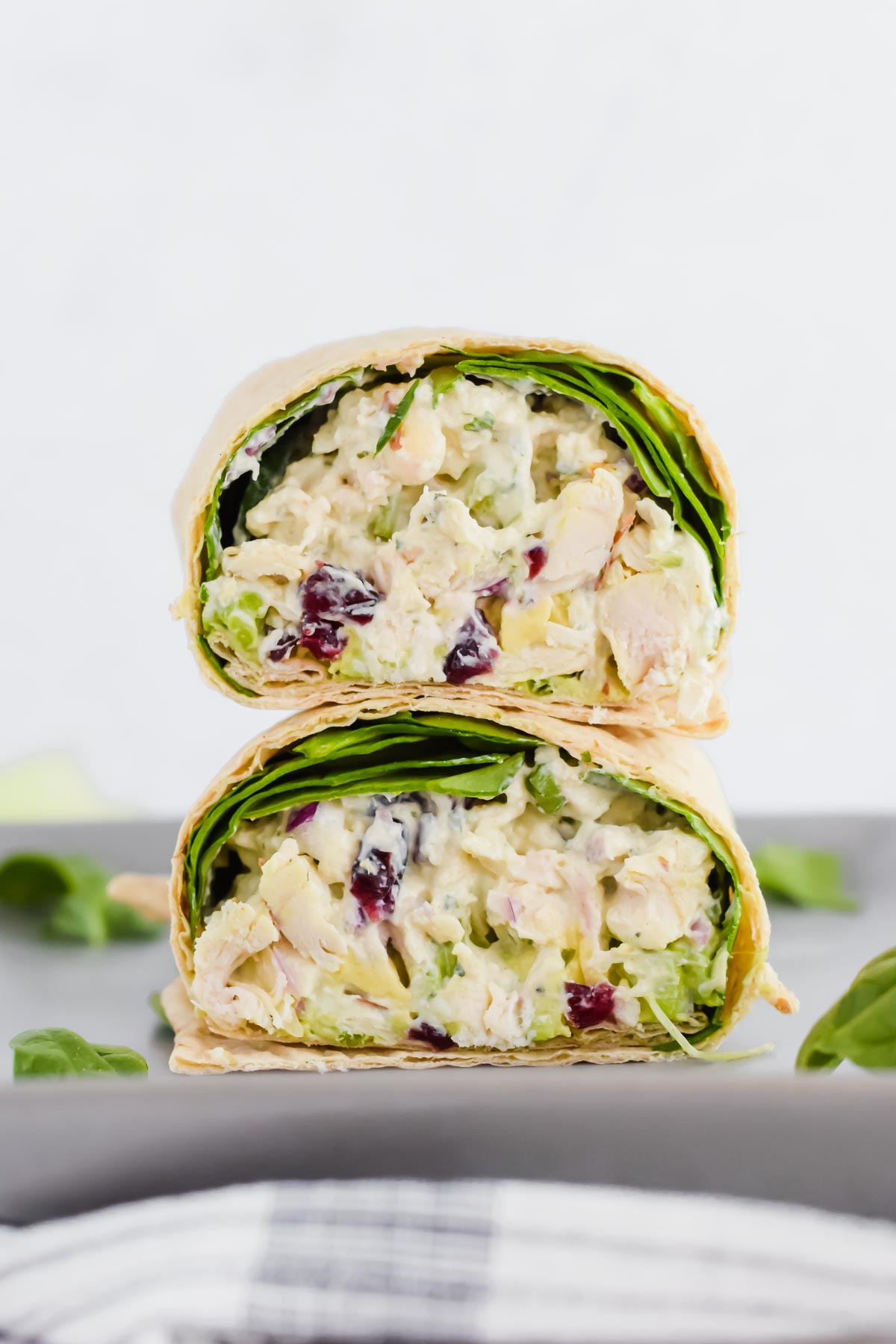 healthy pesto chicken salad in a wheat wrap on a grey plate with concrete background.